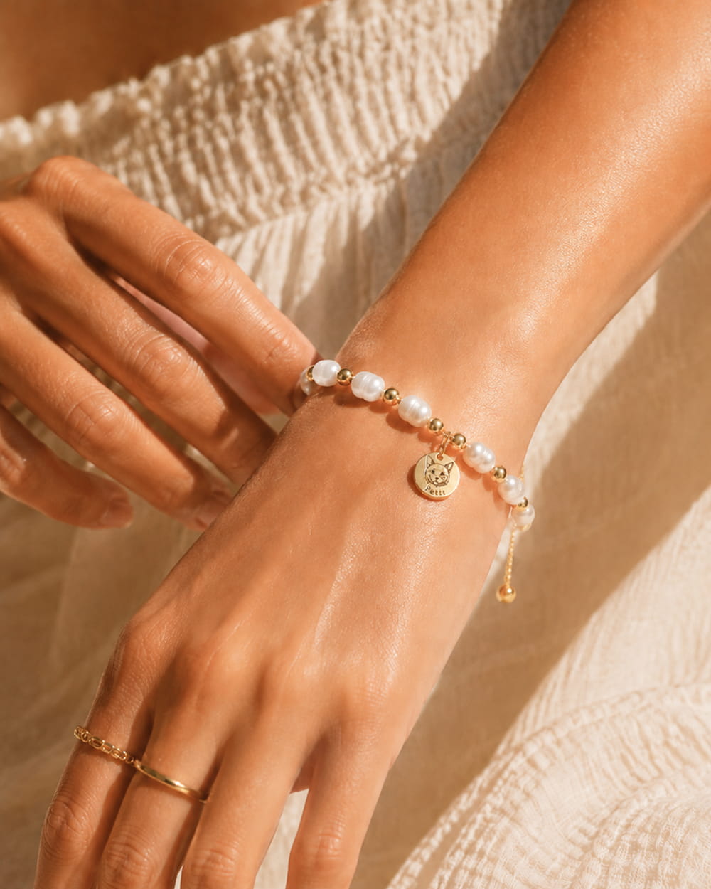 Custom pet bracelet on hand with angel wings photo charm and faux pearl strand.